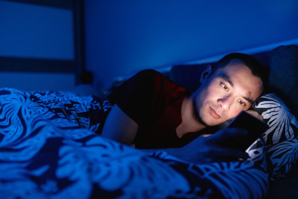 man on his phone in bed at night