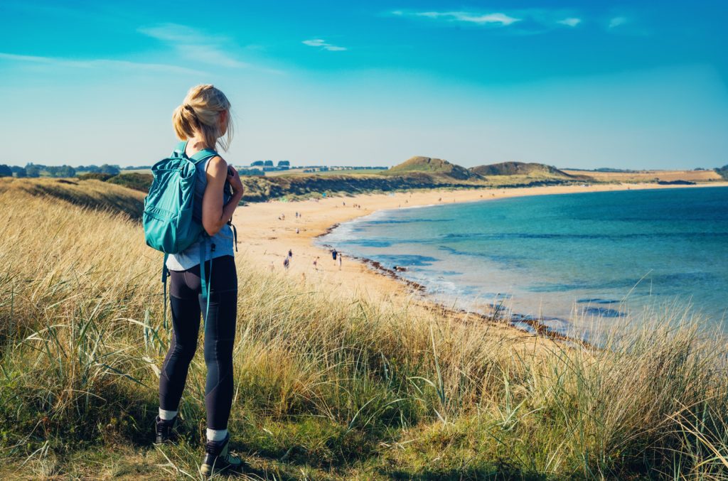 woman stood on hill above beach